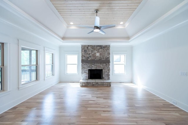 unfurnished living room featuring a raised ceiling, ceiling fan, a fireplace, and wood finished floors