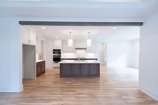 kitchen with light countertops, white cabinets, light wood finished floors, and tasteful backsplash