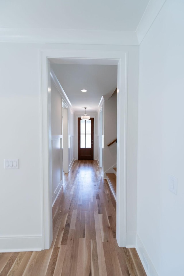 corridor with baseboards, light wood finished floors, stairs, and a chandelier