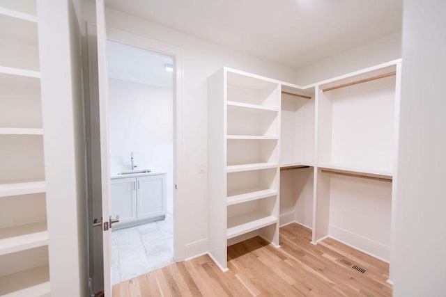 spacious closet with visible vents, a sink, and light wood-style floors