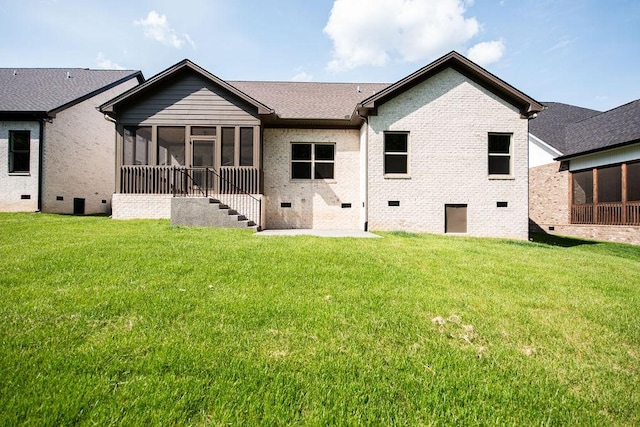rear view of house with a yard, crawl space, brick siding, and a sunroom