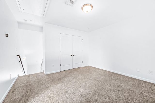 unfurnished bedroom featuring carpet floors, attic access, baseboards, and visible vents