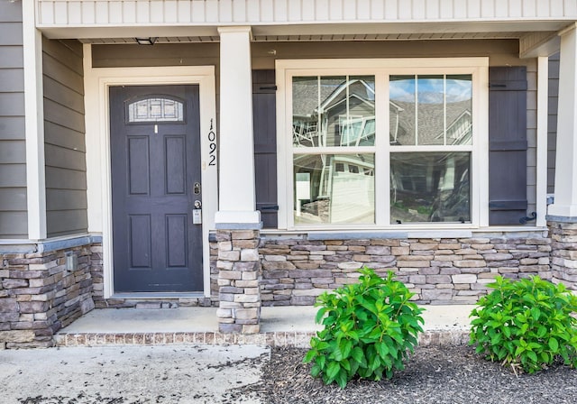 doorway to property featuring a porch and stone siding