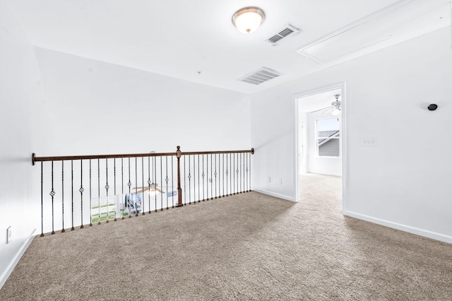carpeted empty room featuring baseboards, visible vents, and attic access