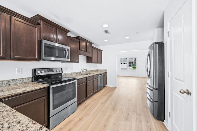kitchen featuring dark brown cabinets, a sink, light wood-style flooring, stainless steel appliances, and visible vents