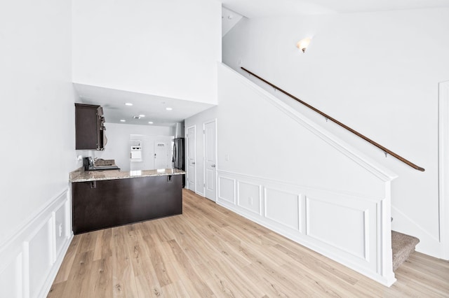 interior space featuring freestanding refrigerator, a decorative wall, a peninsula, and light stone countertops