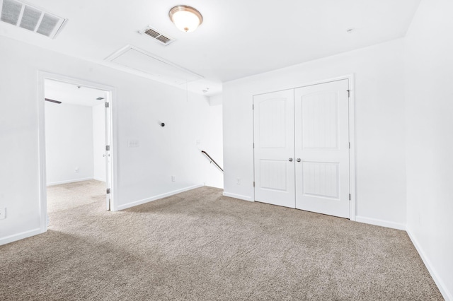 carpeted spare room featuring baseboards, attic access, and visible vents