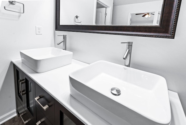 full bath with double vanity, a sink, baseboards, and ceiling fan