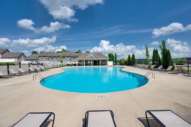community pool with fence, a residential view, and a patio area