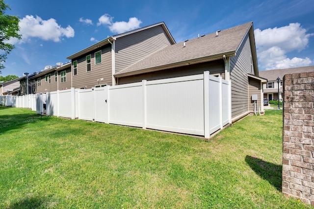 back of house with a lawn, fence, and a shingled roof