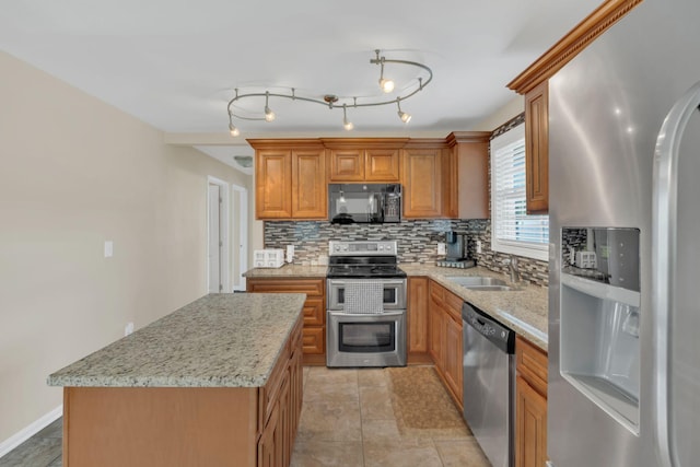 kitchen with light stone counters, a sink, stainless steel appliances, decorative backsplash, and a kitchen island