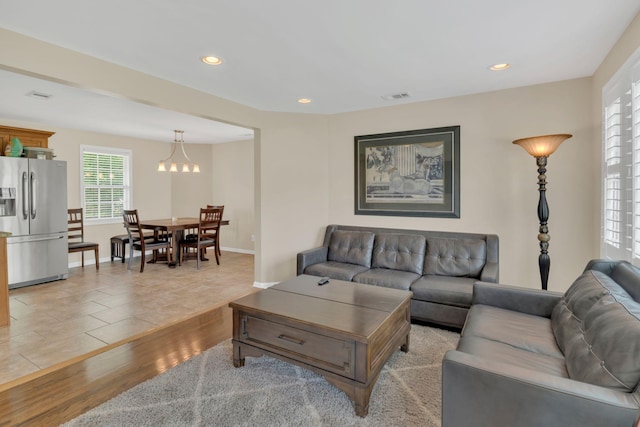 living area with visible vents, baseboards, light wood finished floors, a notable chandelier, and recessed lighting