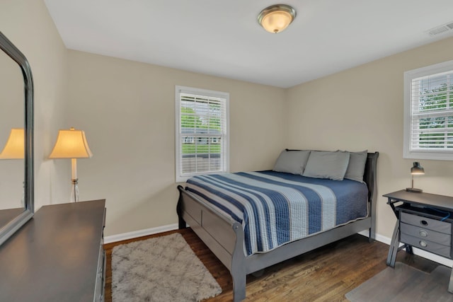 bedroom with baseboards, visible vents, multiple windows, and wood finished floors