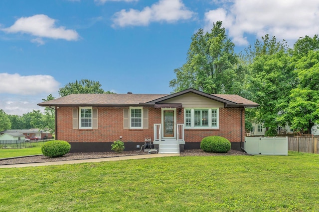 single story home featuring brick siding, fence, and a front yard