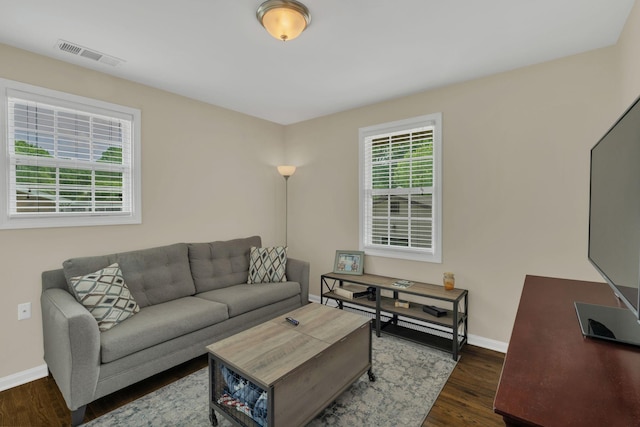 living area featuring visible vents, dark wood finished floors, and baseboards