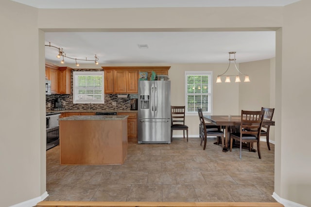 kitchen with appliances with stainless steel finishes, baseboards, decorative backsplash, a kitchen island, and visible vents