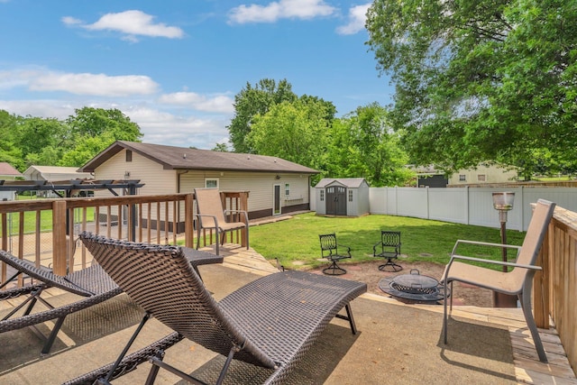 view of patio with a deck, an outbuilding, a fenced backyard, a storage unit, and a fire pit