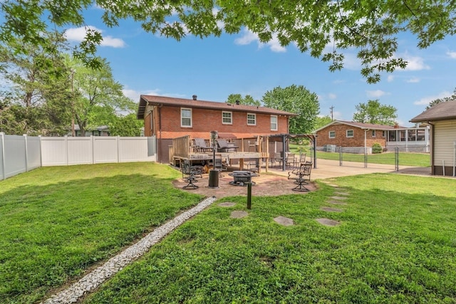 rear view of house featuring brick siding, a fenced backyard, a lawn, a patio, and a fire pit