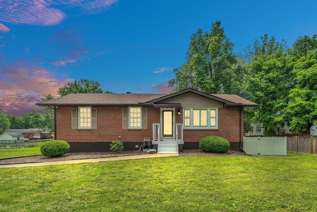 view of front facade with brick siding, fence, and a front lawn