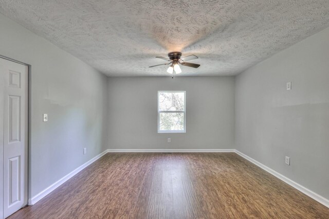 spare room with baseboards, a ceiling fan, dark wood-style flooring, and a textured ceiling