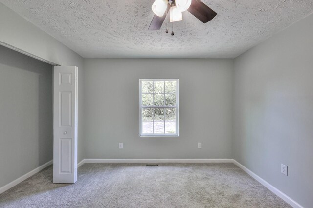 unfurnished bedroom featuring carpet floors, a ceiling fan, a textured ceiling, and baseboards