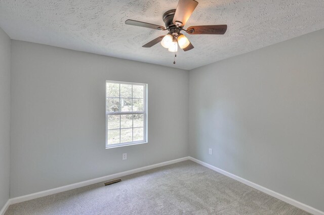 carpeted spare room featuring baseboards, a textured ceiling, ceiling fan, and visible vents