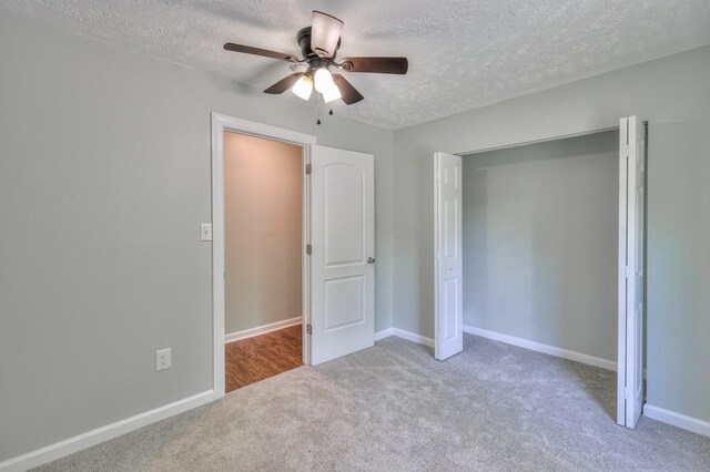 unfurnished bedroom with ceiling fan, a textured ceiling, carpet floors, baseboards, and a closet