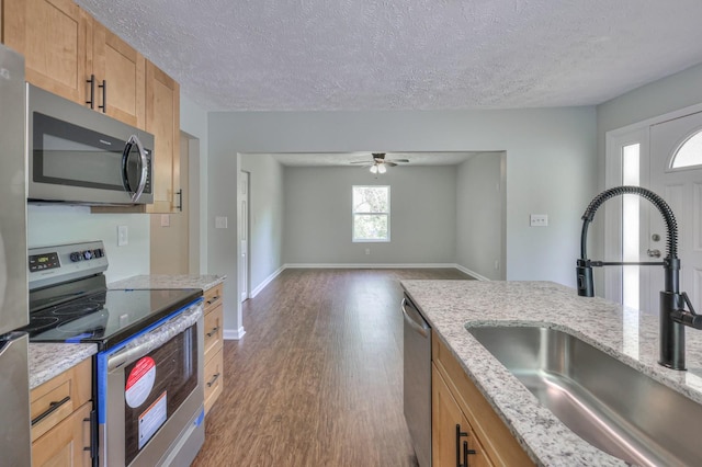 kitchen with ceiling fan, a textured ceiling, appliances with stainless steel finishes, wood finished floors, and a sink
