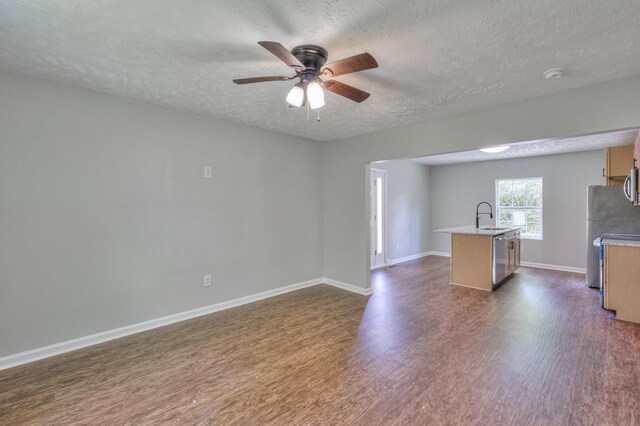 unfurnished living room featuring a sink, ceiling fan, dark wood-style flooring, and a textured ceiling