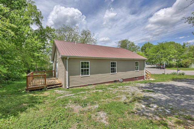 view of home's exterior with a deck, a yard, crawl space, and metal roof