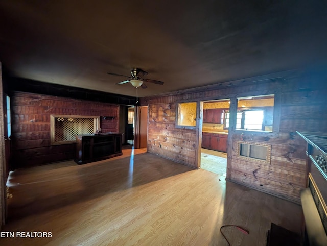 living area featuring wood walls, ceiling fan, and wood finished floors