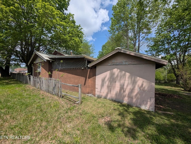 view of property exterior featuring concrete block siding, fence, and a yard
