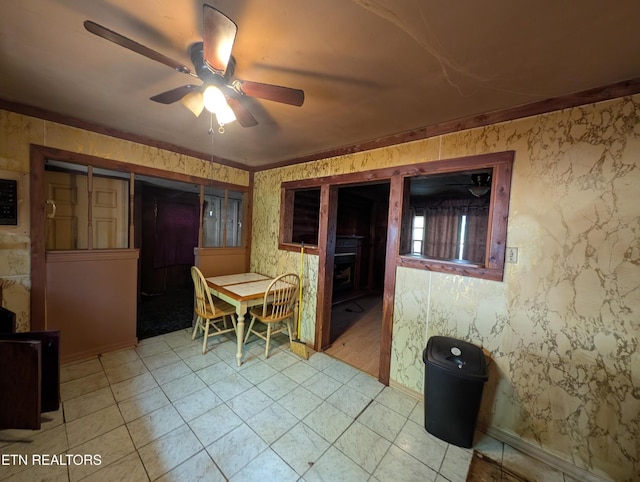dining room featuring light floors, ceiling fan, and a fireplace