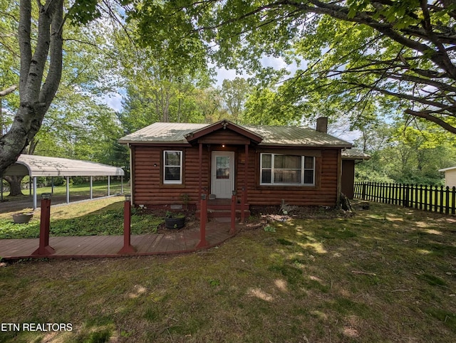 view of front facade with log veneer siding, a chimney, metal roof, a front yard, and fence