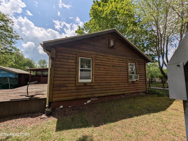 view of property exterior with a lawn, log veneer siding, fence, and a wooden deck