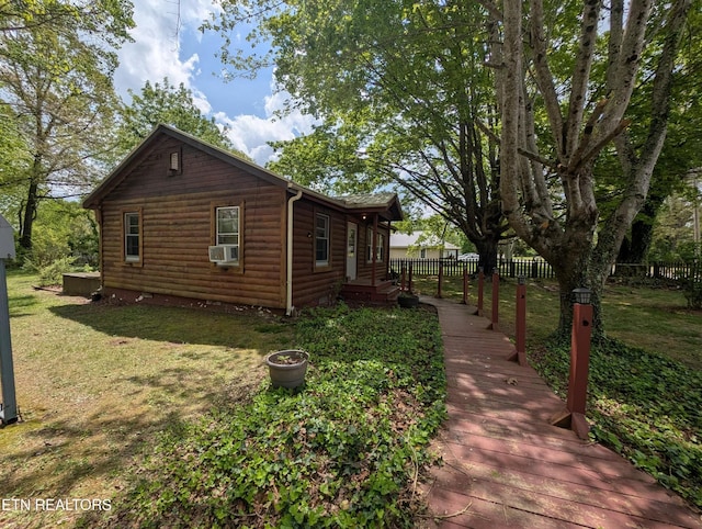 view of home's exterior with fence, faux log siding, and a lawn