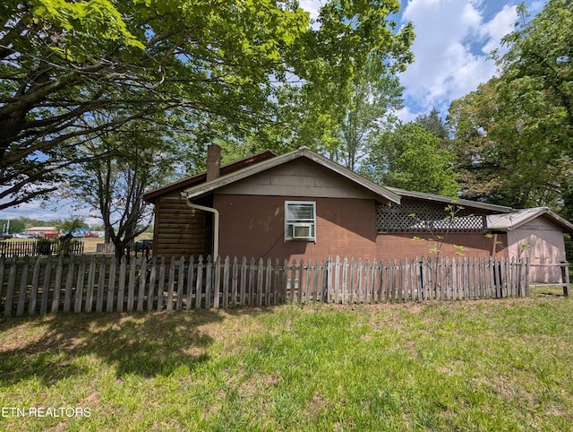 view of side of home with fence, a chimney, and a lawn