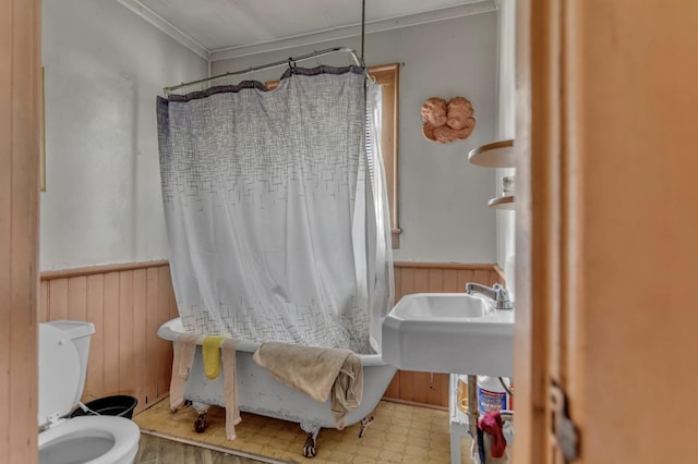 full bath with shower / bath combo with shower curtain, ornamental molding, wainscoting, toilet, and tile patterned floors