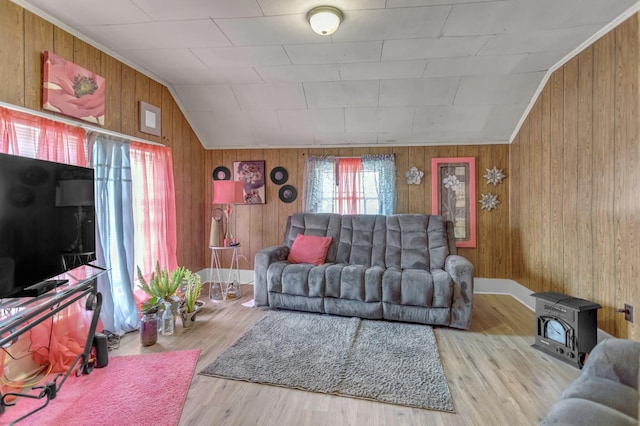 living area with wooden walls, vaulted ceiling, a wood stove, and wood finished floors