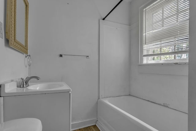 bathroom with a bathtub, walk in shower, wood finished floors, vanity, and toilet