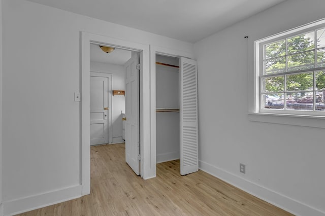 unfurnished bedroom featuring a closet, light wood finished floors, and baseboards