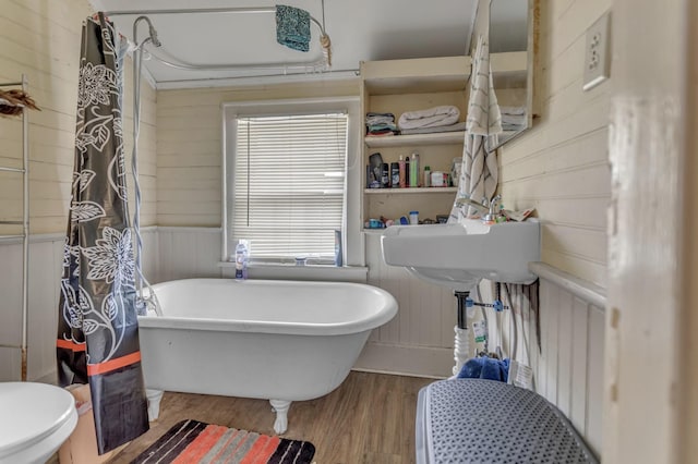 full bathroom with wooden walls, a freestanding bath, toilet, radiator heating unit, and wood finished floors
