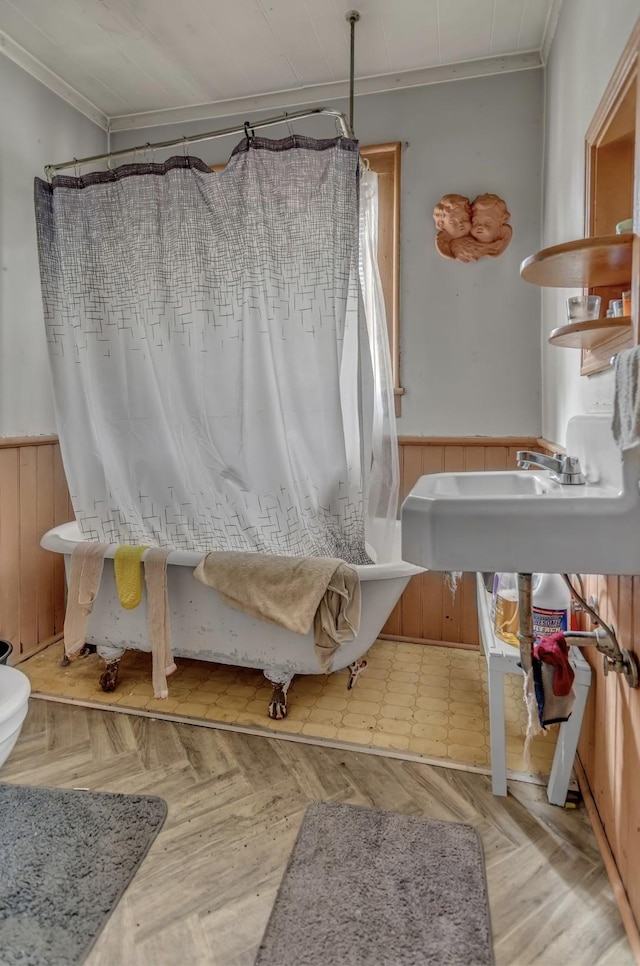 full bath with crown molding, a wainscoted wall, wooden walls, and a shower with curtain