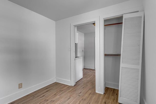 unfurnished bedroom with a closet, baseboards, and light wood-style floors