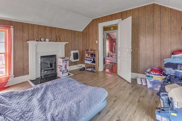 bedroom with heating unit, wood finished floors, and lofted ceiling