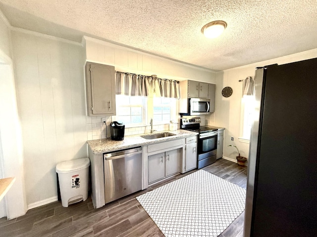 kitchen featuring appliances with stainless steel finishes, a sink, light countertops, gray cabinetry, and dark wood-style floors