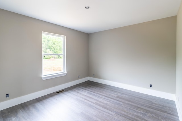 unfurnished room featuring visible vents, baseboards, and wood finished floors