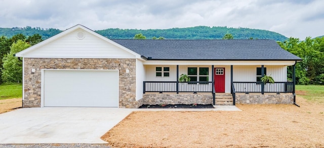 ranch-style house featuring roof with shingles, stone siding, a garage, covered porch, and driveway