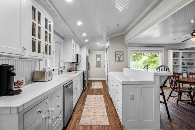 kitchen with crown molding, appliances with stainless steel finishes, a kitchen island, recessed lighting, and dark wood finished floors