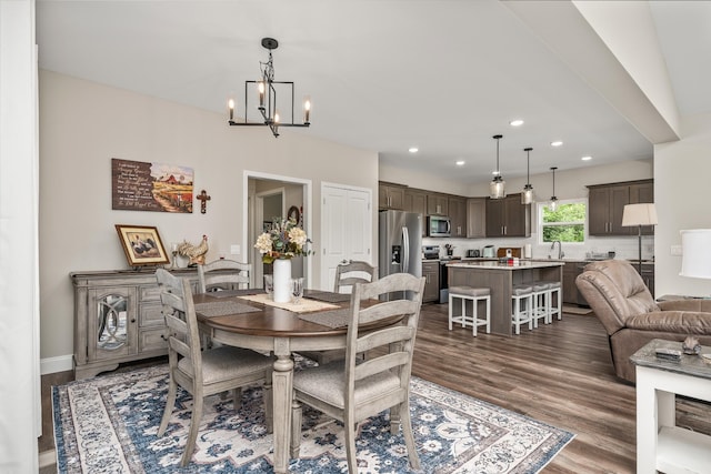 dining area with dark wood-type flooring, recessed lighting, baseboards, and a notable chandelier